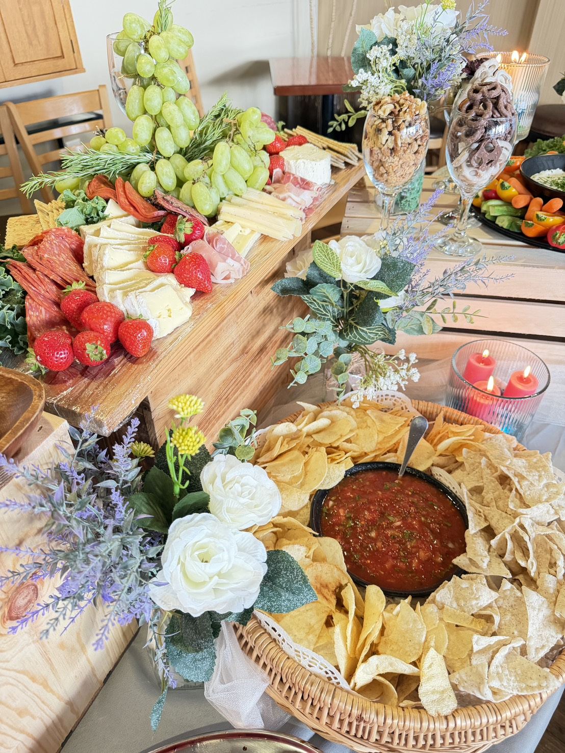 Catering table with charcuterie, chips and salsa, florals and candles